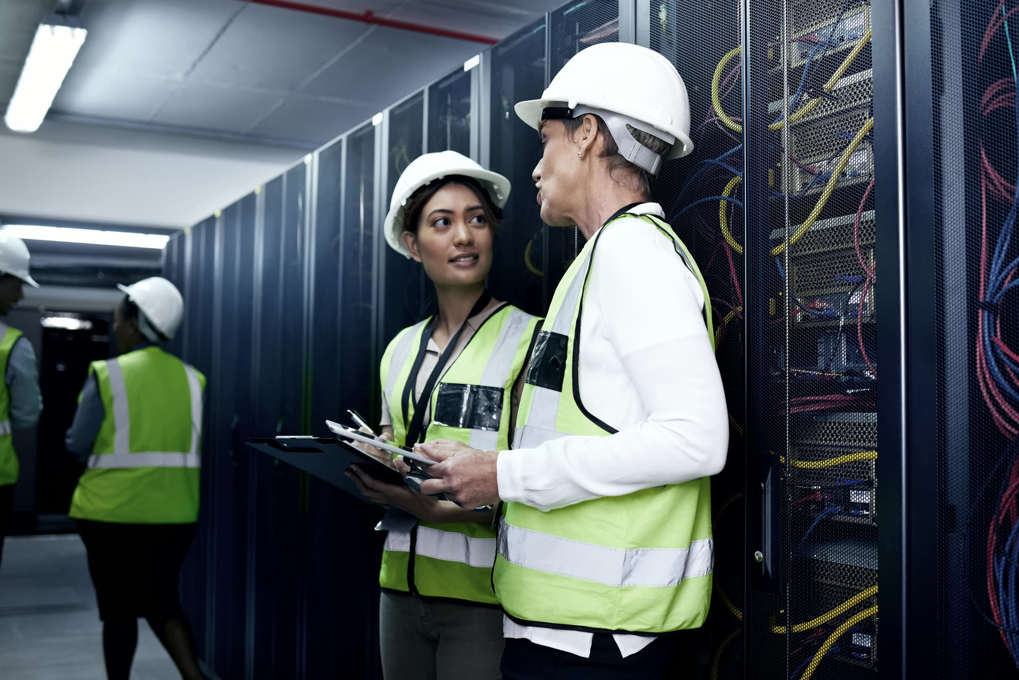 Engineers in hard hats and hi-vis reviewing a data hall