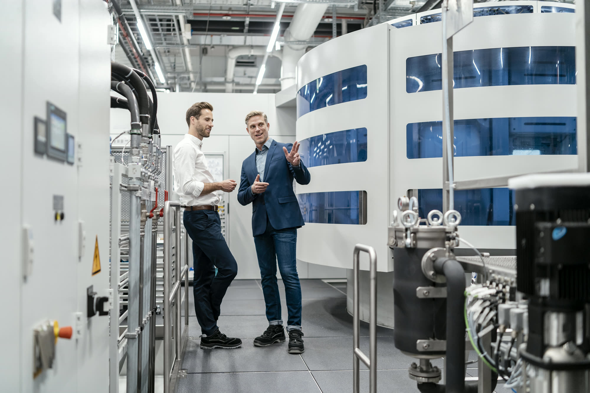 Two senior leaders in conversation inside a modern data centre plant room