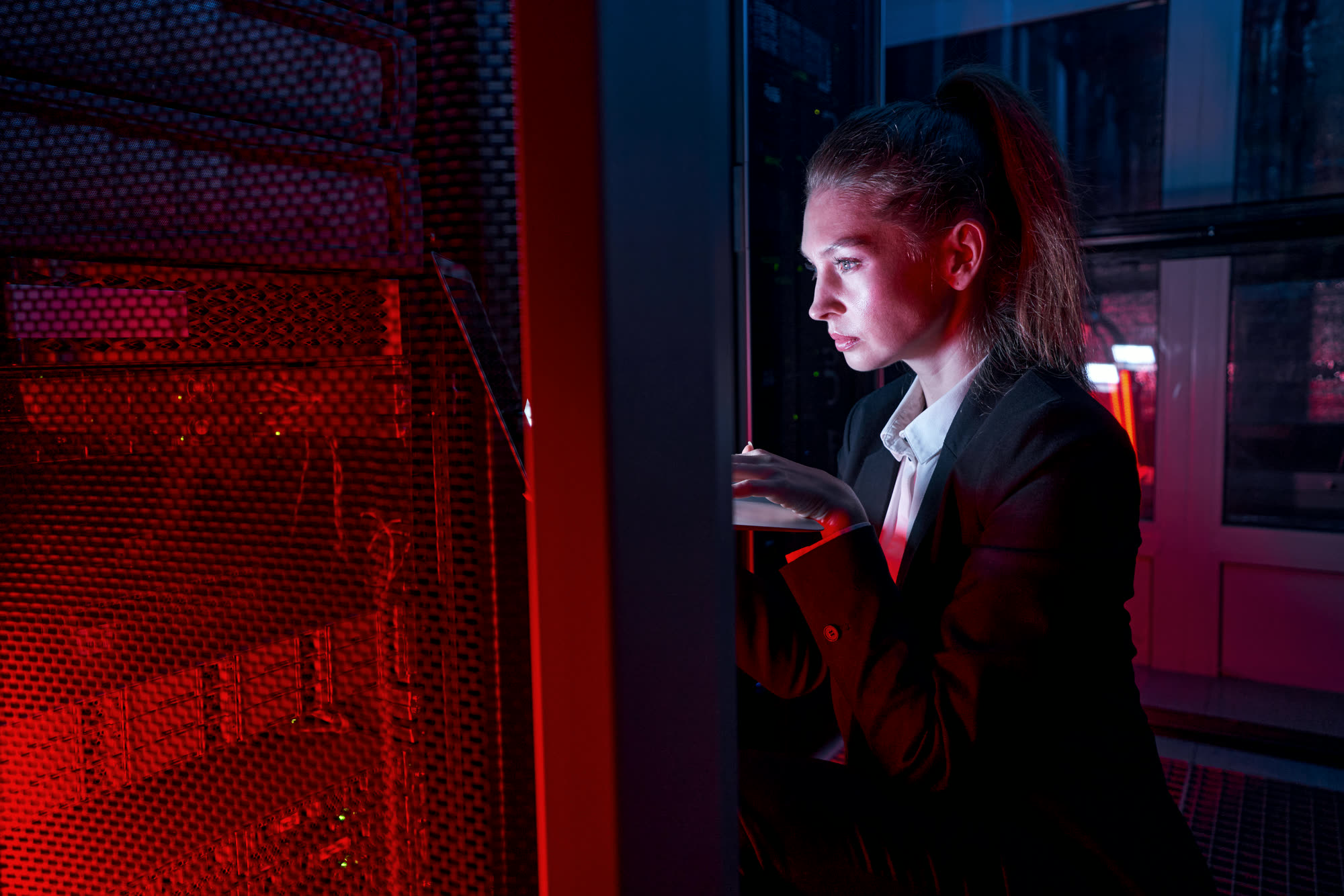 An engineer working on servers under red light in a data centre